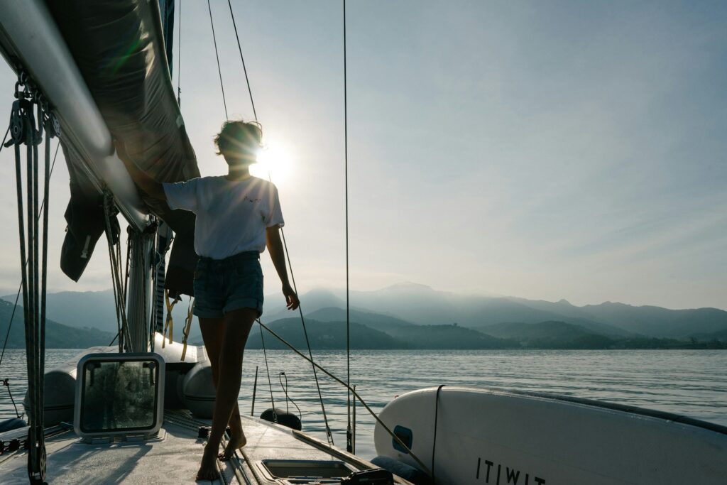 yacht, woman on a yacht, body of water, sea, sky, mountains