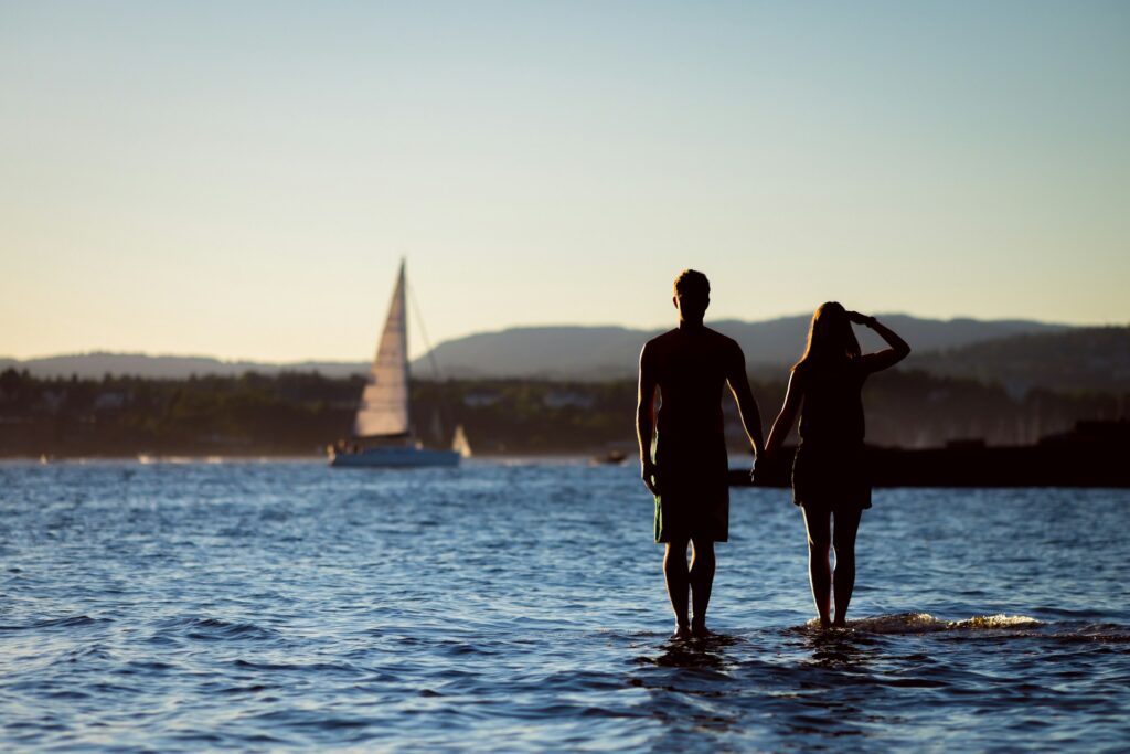 yacht, tour, couple standing on a body of water, water, mountains, sea